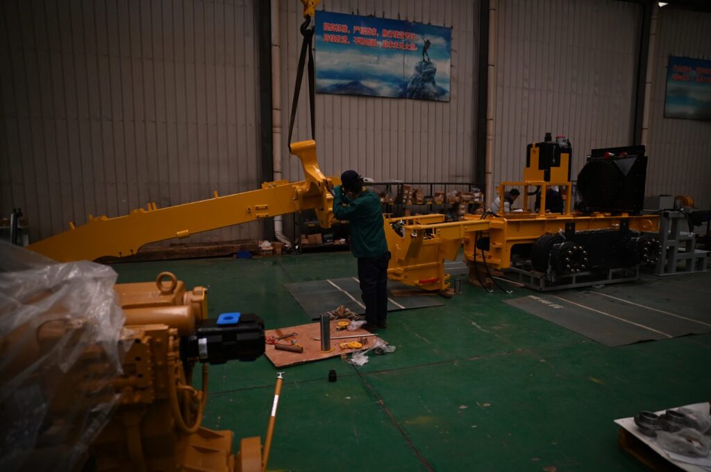 Worker assembling motor grader arm